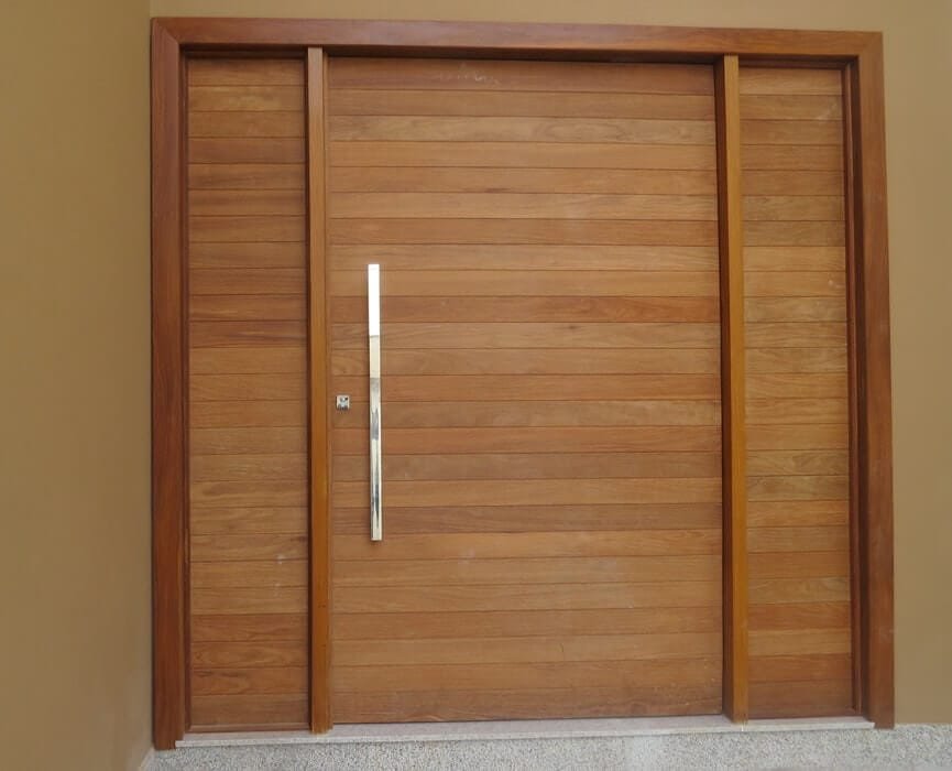 Porta de madeira com duas partes fixas laterais complementando o vão